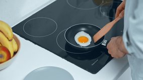 partial view of man cooking scrambled egg for breakfast in kitchen