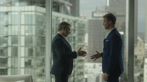 Two business partners do handshake in front of view on downtown and skyscrapers. A good business deal.