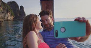 Couple taking selfie photo or video with smartphone on long tail boat tour in Asia Thailand. Asian summer holiday travel vacation adventure. Slow motion travel hand held in Asia.  Shot on red.