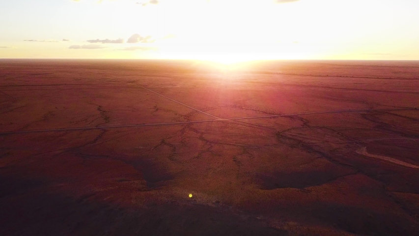 High panning aerial shot of incredible sunset over immense red earth plains of the Australian outback. Location Mundi Mundi Plains, Australia.
