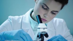 beautiful, attentive scientist looking in microscope while working in laboratory