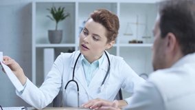 selective focus of attractive doctor holding cardiogram and talking to colleague