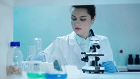 pretty, concentrated scientist making analysis with microscope in clinical laboratory