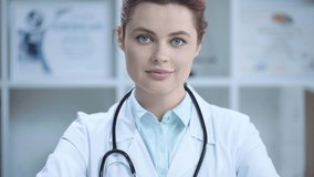 cheerful young doctor in white coat smiling and looking at camera