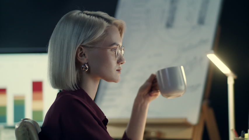 Concentrated business woman drinking coffee front computer in night office. Overworked businesswoman drinking tea at late work. Portrait of tired lady working at workplace. | Shutterstock HD Video #1032537554