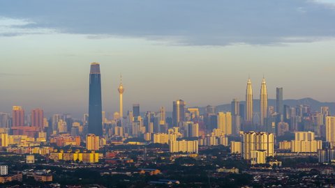 Time lapse: Foggy and dramatic first light sunrise view of Kuala Lumpur city skyline from afar and high angle in Malaysia at dawn.