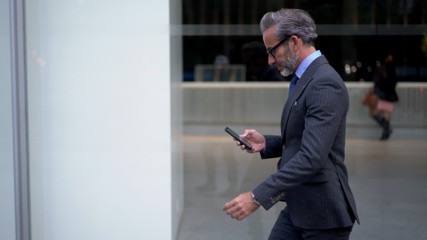 Slow motion effect, Caucasian businessman dressed in formal suit browsing network website using modern smartphone gadget. Middle aged man using mobile phone outdoors in city | Shutterstock HD Video #1032547253