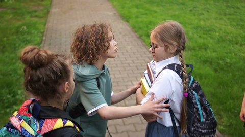 Group of teenagers are pushing and insulting a schoolgirl. Adolescent violence problem. Bullying among adolescents and schoolchildren. Physical violence