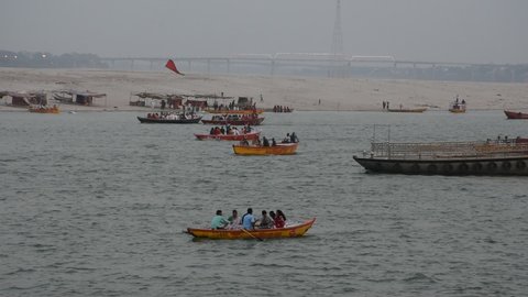 Varanasi, India - June 2019: Ghats of Ganges river with big, small running boats during Ganges ceremony (Aarti) in Varanasi. Beauty of Varanasi ghats from river with boats, water, people and buildings