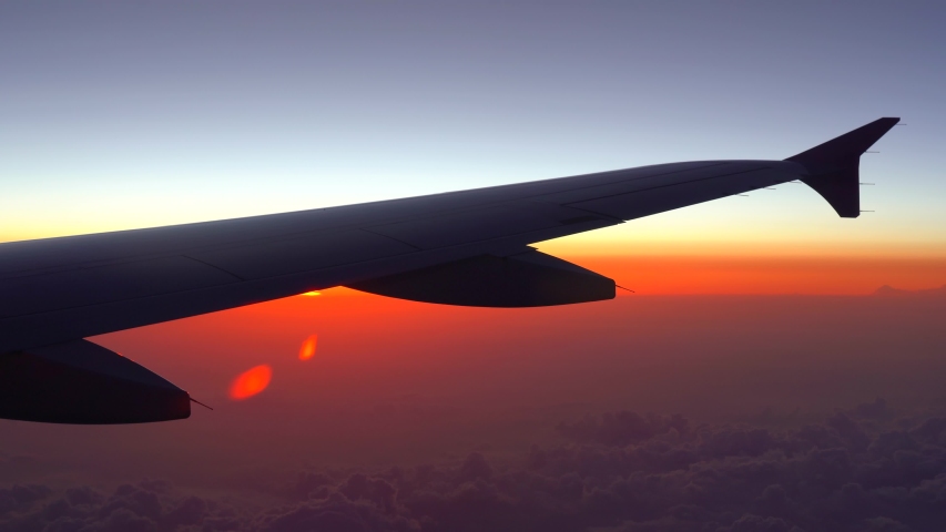 Up in the air, view of aircraft wing silhouette with dark blue sky horizon and cloud background in sun rise time, viewed from airplane window Royalty-Free Stock Footage #1032553250