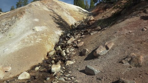 Lassen Volcanic National Park- A view of volcanic rock formations with a small snow stream melt off from the mountains above.
