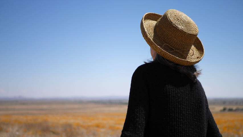 A smiling old woman with gray hair laughing in a summer field of orange flowers under blue sky SLOW MOTION.