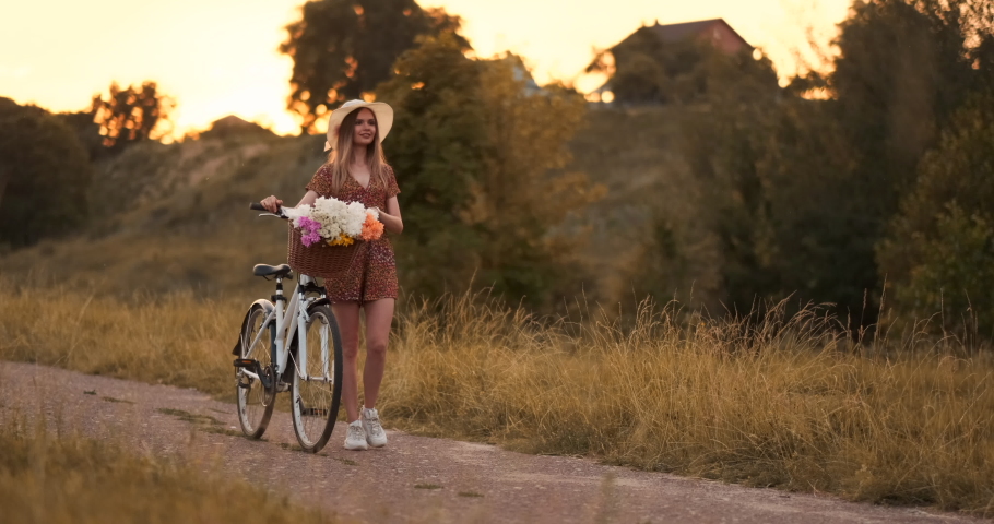 Summer in the field girl goes with a bike on the road