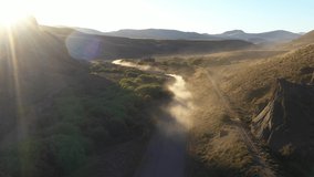 Drone aerial view of two vehicles driving on a dirt road raising dust on a dirt road in Rio Negro Province, Patagonia Argentina
