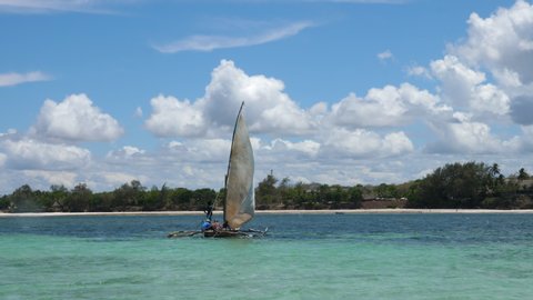 Static, shot of a people on a sailboat,ing out, in turquoise water, at the coast of Mombasa, on a sunny day, in Kenya, Africa