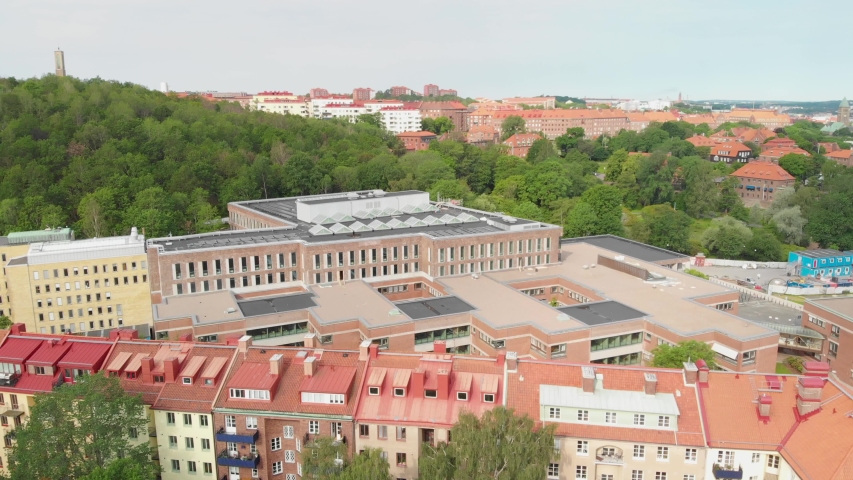 Aerial video of beautiful old apartment buildings and Gothenburg university humanistic faculty with lots of lush bushes and greenery behind the buildings