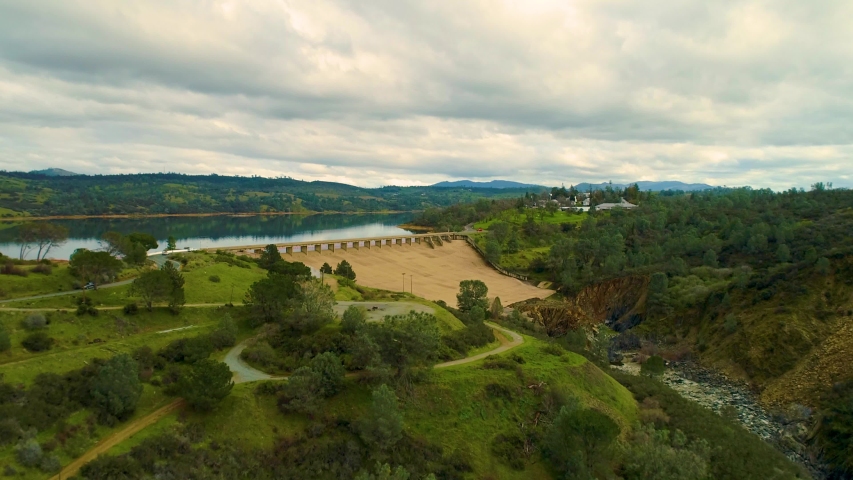 Aerial View  Dam Village waterfront  4K Helicopter Shot  landmark trees road cars cloudes california lake
