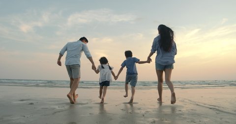 SLOW MOTION - Asian family running on the beach at sunset with happy emotion. Family, Holiday and Travel concept. Back Rear View.
