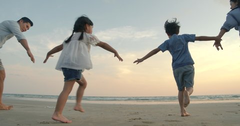 SLOW MOTION - Asian family running on the beach at sunset with happy emotion. Family, Holiday and Travel concept. Back Rear View.
