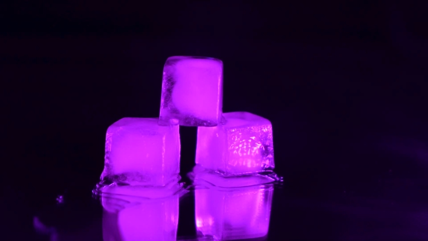 three ice cubes for cocktail with violet backlight and smoke