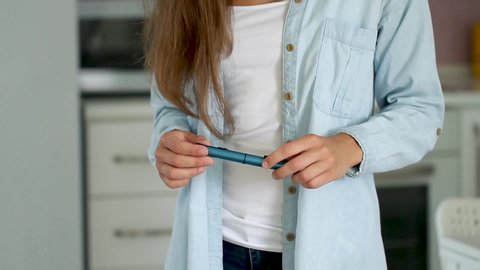 A diabetic patient using insulin pen for making an insulin injection at home. Young woman control diabetes. Diabetic lifestyle 