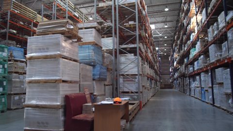 Huge logistic warehouse. Panorama between the rows with shelves. The warehouse is filled with products in boxes.