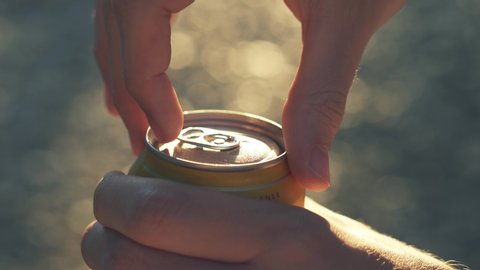 Opening misted wet can of beer sun backlight outdoors