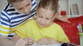 Two cute schoolchildren boy and girl doing homework together at home