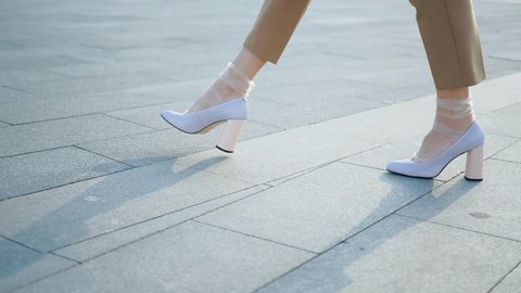 Legs walking. Female feet on heels and in trendy nylon socks