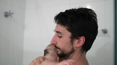 Father holding baby in the shower bathing and washing, dad bonding with baby son, real life