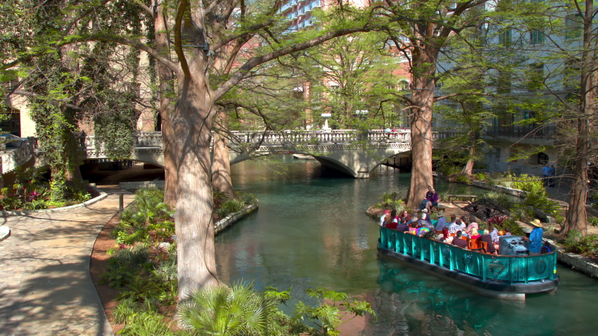 San Antonio TX Scenic Nature River Walk with Tourists in a Boat on a Sightseeing Tour under the Green Tree Canopy of the Popular Downtown Attraction
