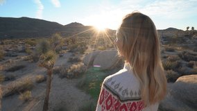 4K video of Happy young woman makes heart shape finger frame on nature landscape at sunset; love people embracing life concept- Joshua tree park 