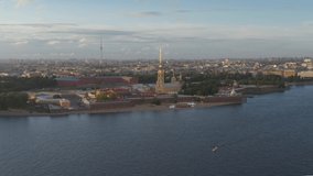 Aerial video of center of Peter and Paul fortress at sunset, Saint Petersburg, Russia, boats on the Neva river, golden spire, cathedral