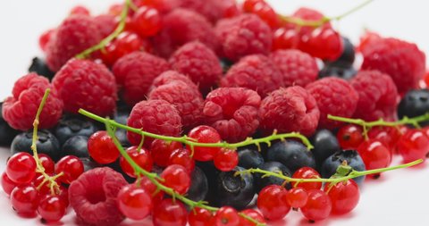 forest berries rotate on a white background and fall from above. raspberries, currants and blueberries, the concept of a healthy diet and vitamins. natural ingredient
