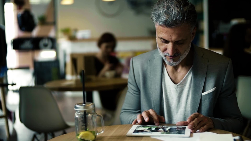 A portrait of a mature businessman sitting in a cafe, using tablet. Royalty-Free Stock Footage #1032675824