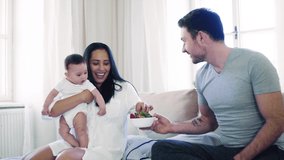Young happy couple with a baby indoors on bed, eating strawberries. - Powered by Shutterstock - Get 15% off with code: PIKWIZARD15