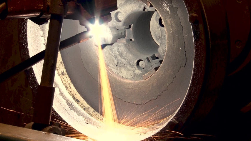 Sparks from hot metal scatter in different directions. Process of applying thermal barrier coatings on elements of hot engine parts. Close-up. Repair of gas turbine engines. - Powered by Shutterstock - Get 15% off with code: PIKWIZARD15