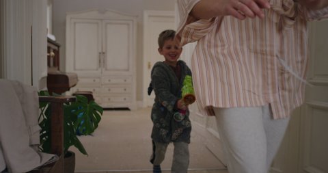 cute little boy blowing bubbles chasing mother with toy gun running through house playing catch mom enjoying fun game with son enjoying weekend morning together 4k footage