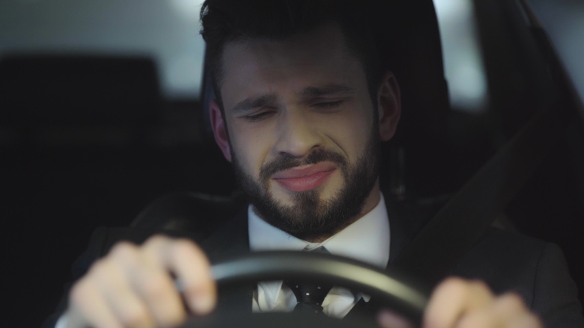 Selective focus of upset bearded man crying while driving car