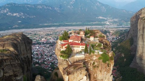 Greece Meteora monasteries in rocks view of cliffs, aerial view of slide from drone panorama of mountain range. Many ancient Orthodox monasteries sunrise Kalampaka city. Travel. Tourism. Unesco world