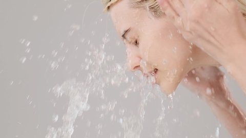 Woman washing her clean face with water. Young adult girl is  washing face with water. Slow motion. Beauty treatments. Skin care. Healthy skin concept. Profile portrait. 