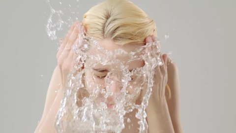 Woman washing her clean face with water. Young adult girl is  washing face with water. Slow motion. Beauty treatments. Skin care. Healthy skin concept. 