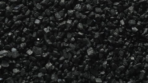 Macro shot of black coal stones shaking and moving forward through vibrations of sound.