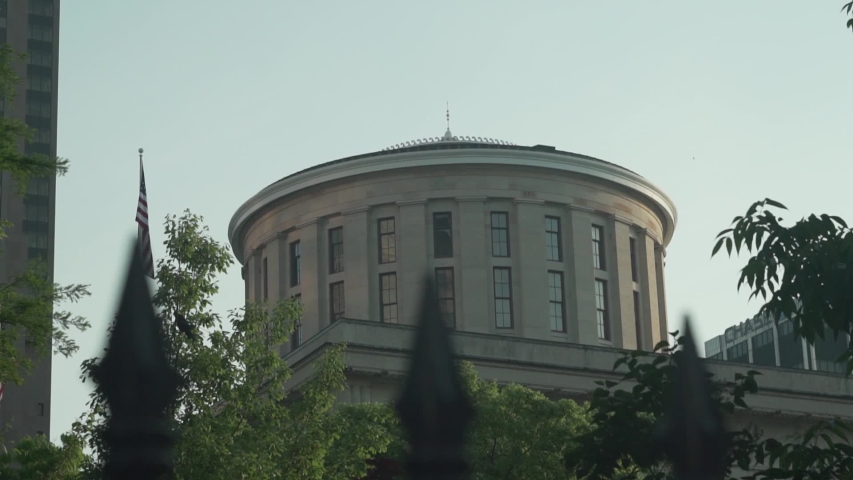 Exterior shot of the Ohio Statehouse state capitol building rotunda with United States flag blowing in slow motion