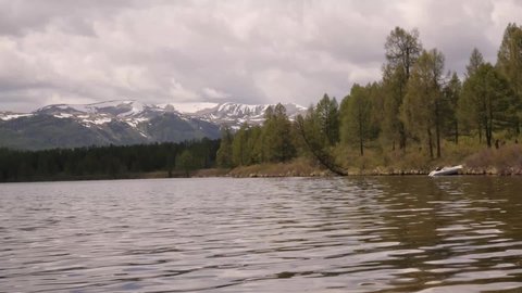 View of mountain lake with storm clouds reflected in a water surface. coniferous forest on the shore