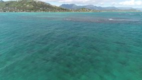 Aerial view of Lanikai beach, Honolulu, Hawaii, low angle view with drone camera moving forward, reef in clear green open water