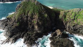 Aerial view of Lanikai beach, Honolulu, Hawaii, low angle view with drone camera moving forward, camera closing in on white waves braking on the rocks of green island in open waters