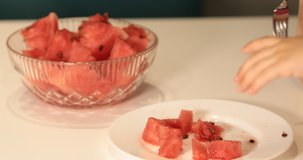 child eating watermelon in white plate on white table next to glass bowl full of cut watermelon 4K video shoot conceptual buy watermelon shoot. 
