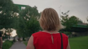 Follow shot of attractive blonde woman in red dress. Clip represents feminity, independence, women entrepreneurship and leadership