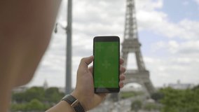 Man using smartphone with Green Screen at Eiffel Tower, Swiping and Scrolling on Touch Screen with Tracking Markers. Browsing Internet, Watching Media Content, Videos, Blogs, Social Networks. 4K UHD.